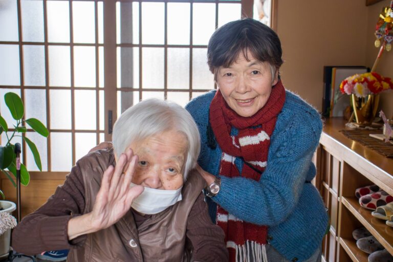 施設内で2人の入居者が笑顔で写るポートレート写真。居室での交流風景。